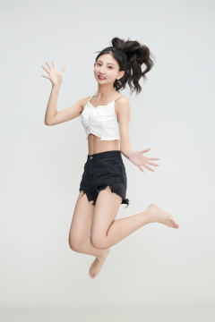 白色背景下腾空跳跃的可爱亚洲少女