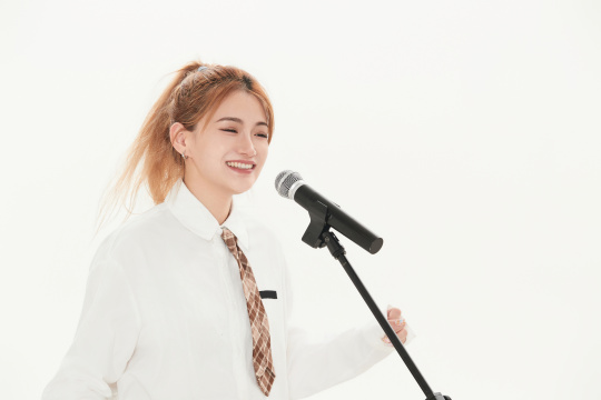 白色背景下站在麦克风前唱歌的亚洲女性