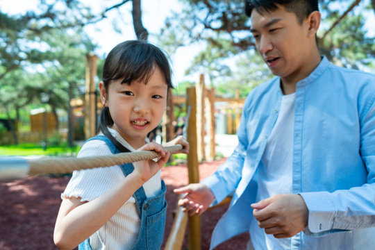 爸爸保护帮助女儿玩攀爬架