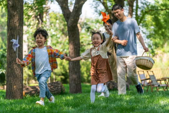 一家四口露营在草地上开心奔跑