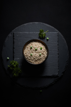 黑色青石板上的木质勺子装的燕麦米摆放在黑色背景中