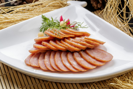 寿司帘上的扇形瓷盘装的自制蒜味香肠