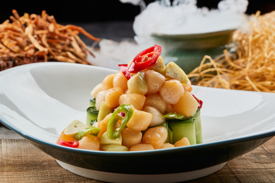 陈旧木板上的月牙瓷盘装的蒜香瑶柱带子