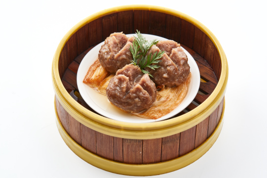 白色背景上精美竹笼屉装的开花牛肉球