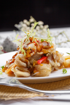 白色瓷盘装的铁板香辣扇贝肉摆放在草垫上