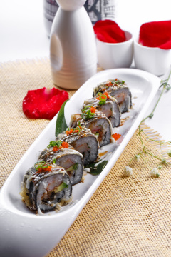 椭圆长瓷盘装的鹅肝手卷寿司摆放在草垫上