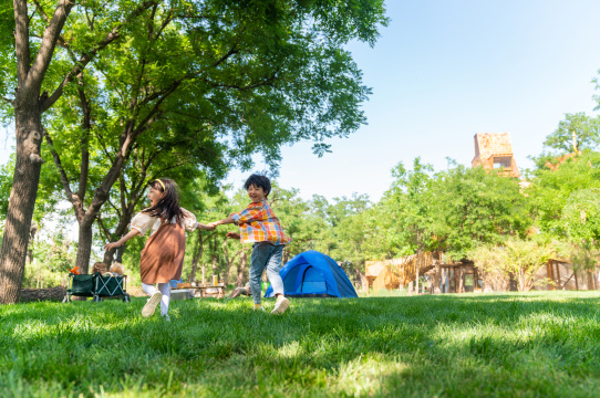 两个孩子在草地上手拉手开心奔跑回头看