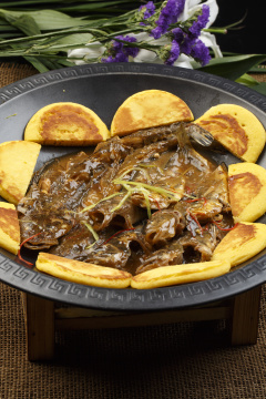 黑色铁锅装的垮炖海鲜杂鱼贴饼子