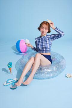 一位 20 多岁的韩国女性，穿着防晒服，坐在游泳圈上，拿着道具 