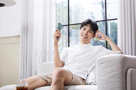 夏日日常_使用手持风扇感到凉爽的男子照片图像 