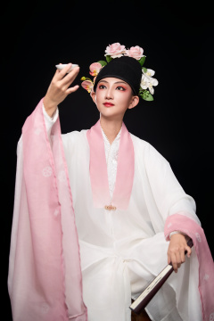 身着粤剧反串装扮手持酒杯折扇的青年女性