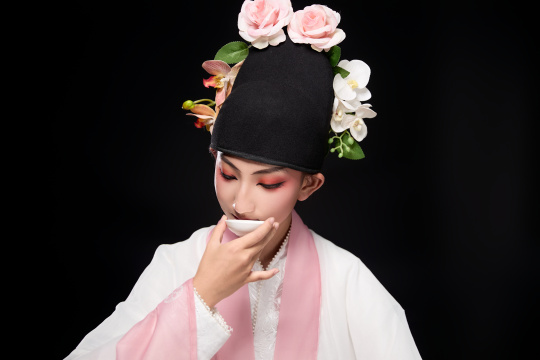 身着粤剧反串装扮手持酒杯折扇的青年女性