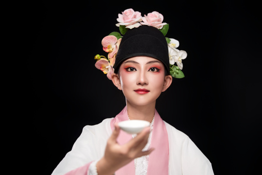 身着粤剧反串装扮手持酒杯折扇的青年女性