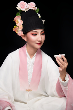 身着粤剧反串装扮手持酒杯折扇的青年女性