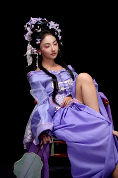 身着簪花仕女装扮坐在木桌上的东方女性