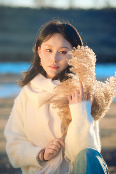 秋天在夕阳下的原野河边拍照的美女