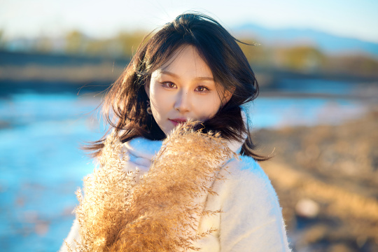 秋天在夕阳下的原野河边拍照的美女