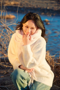 秋天在夕阳下的原野河边拍照的美女