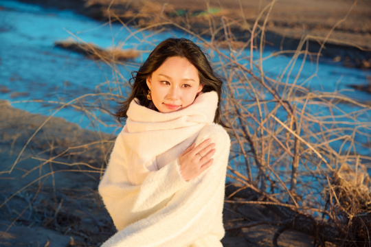 秋天在夕阳下的原野河边拍照的美女