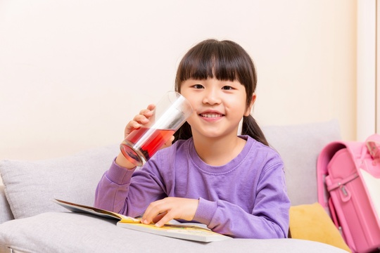 手端玻璃杯喝水的小女孩