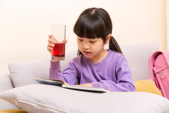 手端玻璃杯喝水的小女孩