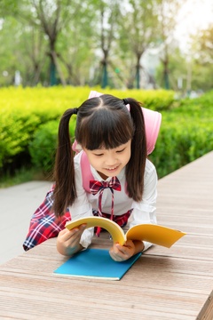 在户外看书的亚洲小学生