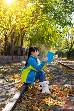 深秋季节在户外看书的亚洲小女孩