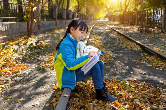 深秋季节在户外看书的亚洲小女孩