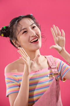 粉色背景下穿背带裤的快乐女孩