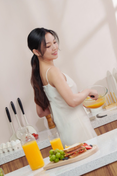 一位亚洲华裔青年女人在厨房里打鸡蛋做早餐