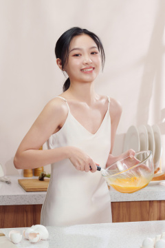 一位亚洲华裔青年女人在厨房里打鸡蛋做早餐