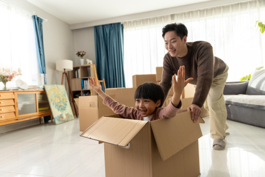 一位可爱的男孩在父亲的陪伴下在纸箱里玩耍