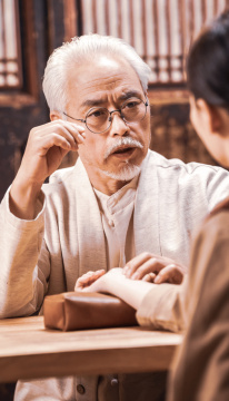 一位亚裔老年中医给患者号脉诊断病情