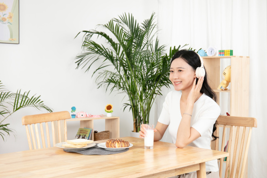 带着耳麦喝牛奶的年轻女性