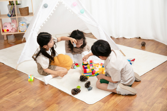 在地毯上玩玩具的三个小朋友