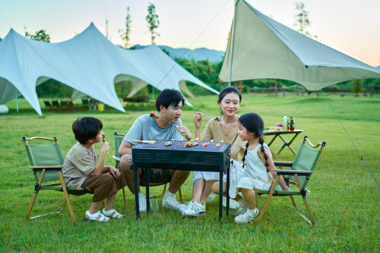 围着烧烤炉吃烧烤的一家四口