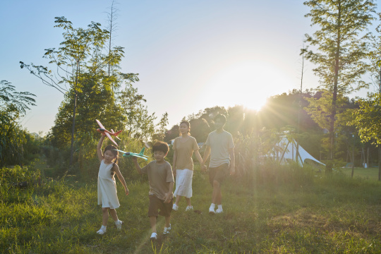 夕阳下手拿飞机模型飞奔的一家四口