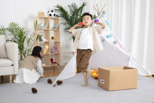 在儿童帐篷前玩纸箱子游戏的两个小朋友