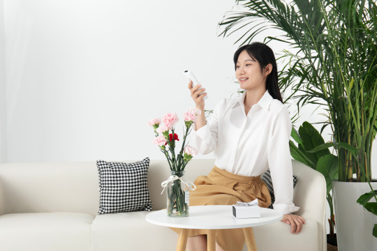坐在沙发上使用遥控器的年轻女人