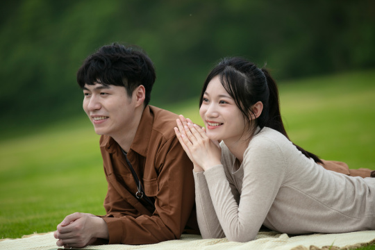 趴在草坪上看前方的年轻情侣