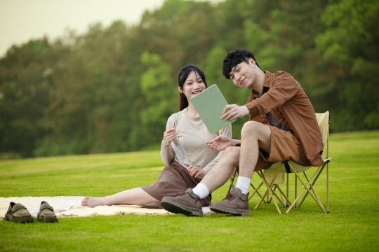 年轻的情侣在草坪上分享平板电脑