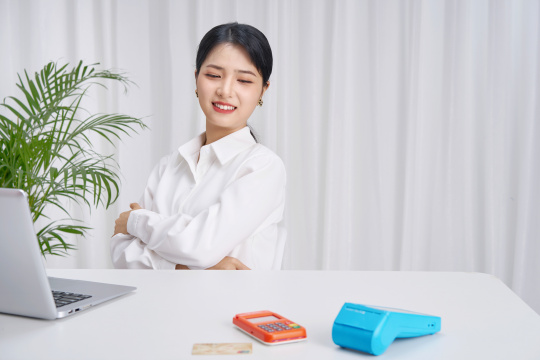 坐在办公桌前使用刷卡机的年轻女性