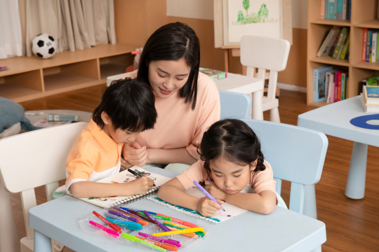 老师坐在桌子旁教教男孩女孩画画