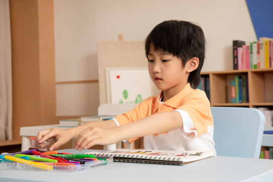 坐在桌子前画画学习的小男孩