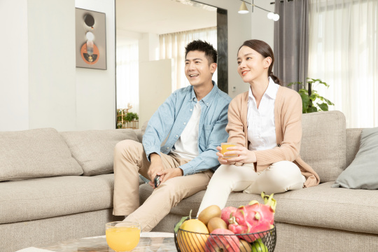 坐在沙发上一起看电视的青年男女