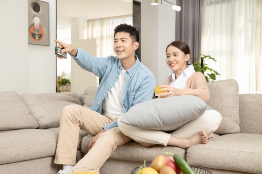 坐在沙发上一起看电视的青年男女