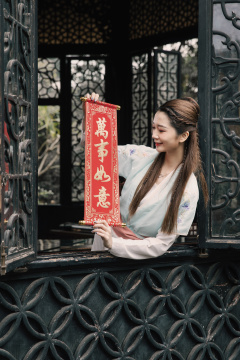 手拿春晖身穿仿古服装的年轻美女