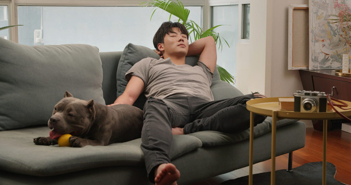 年轻男子和宠物狗在沙发上休息