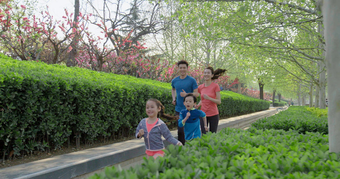 快乐的年轻家庭在公园跑步