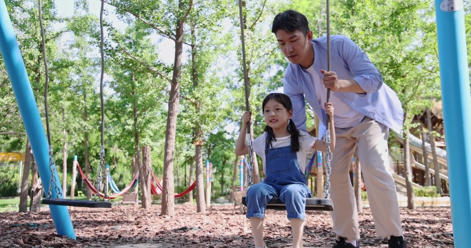 爸爸保护帮助女儿玩秋千